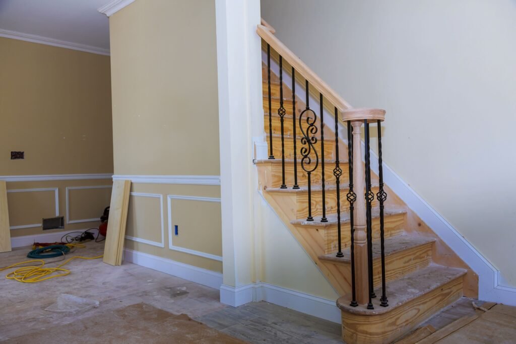 Staircase with wood treads and black wrought iron spindles in a new home under construction.