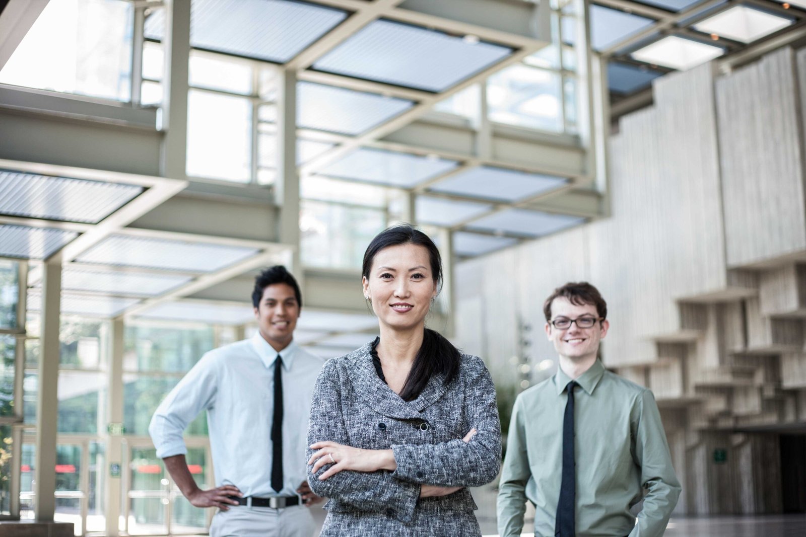 Three business professionals in a modern convention center with a unique architectural ceiling.