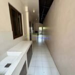A narrow tiled hallway with a sink and cabinets on one side.