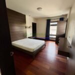 A modern bedroom with a platform bed, dark wood floors, and minimalist decor.