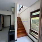 Interior view of a modern home featuring a wooden staircase, tiled floors, a window, and a sleek black console table.