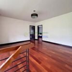 Interior view of a room with hardwood floors, white walls, and a staircase railing.