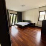 A bedroom with dark wood floors, a bed, and dark curtains.