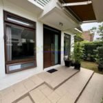Exterior view of a modern home entrance with tiled steps leading to a wooden door, accented by planters.