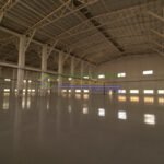 Interior view of a large, empty warehouse with high ceilings and structural beams.