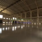 Interior of a large, empty warehouse with a metal roof and concrete floor.