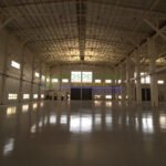Interior view of a large, empty warehouse with high ceilings and polished concrete floors.