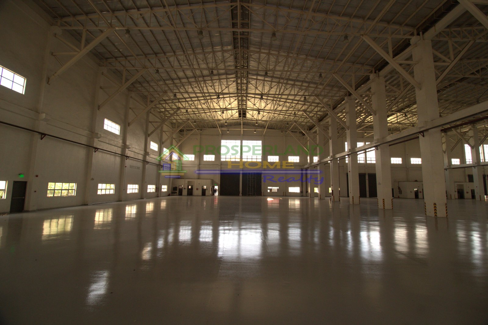 Interior view of a large, empty warehouse with high ceilings and polished concrete floors.