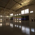 Interior view of a large, empty warehouse with high ceilings and a polished floor.
