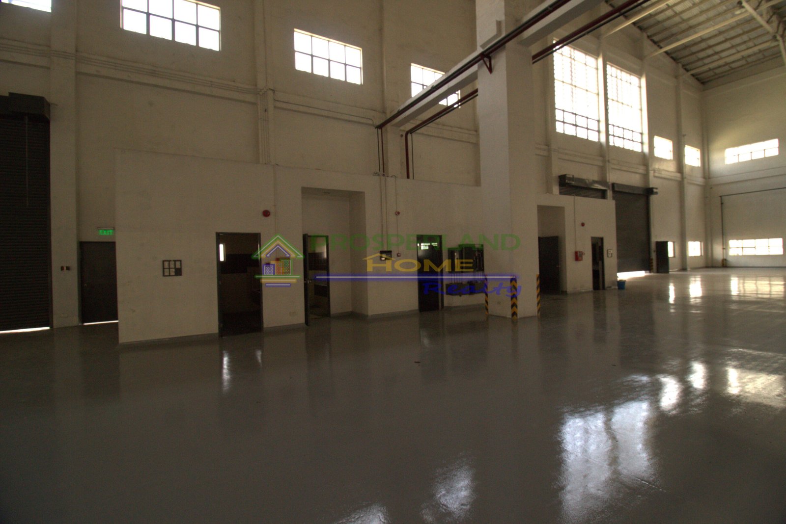 A large, empty warehouse interior with windows and doors.