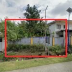 Image of a property lot outlined in red, with a concrete fence, trees, and a house visible in the background.