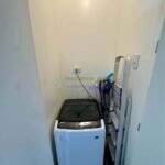 Laundry nook with a top-load washing machine and a folded ladder.