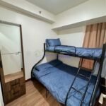 A small bedroom with a bunk bed, wardrobe, and wood flooring.