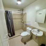 A compact bathroom with shower, toilet, and sink.