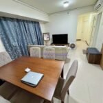 A living room area with a dining table, chairs, a couch, and a TV.