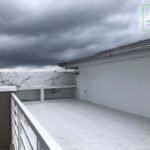A rooftop patio with tile flooring, a built-in counter, and a cloudy sky.