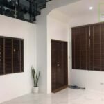 Interior view of a room with wood-slat window blinds and a wooden door.
