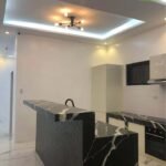 A modern kitchen with black marble countertops and a unique geometric island.