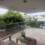 Balcony with glass railings overlooking a neighborhood and lush greenery.