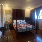 Bedroom with a metal bed frame, red and white patterned blanket, and dark curtains.