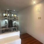 Interior view of a stairway landing with religious figurines and a white bench.