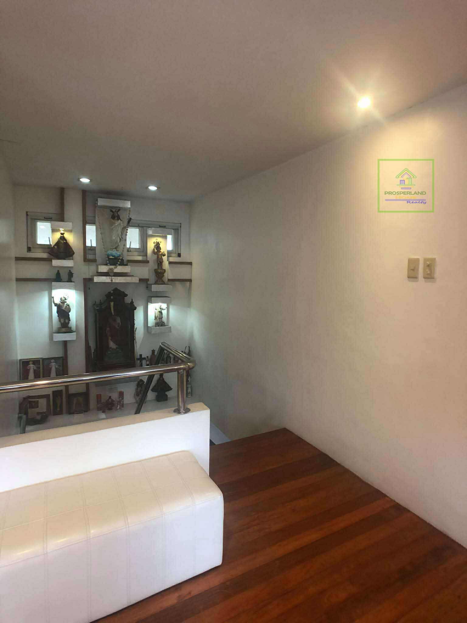 Interior view of a stairway landing with religious figurines and a white bench.