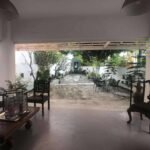 View from covered patio towards an outdoor seating area with plants and a sculpture.