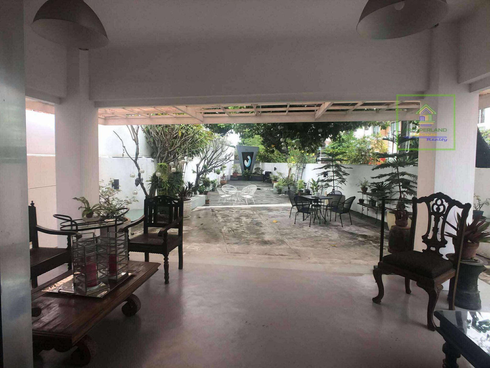 View from covered patio towards an outdoor seating area with plants and a sculpture.