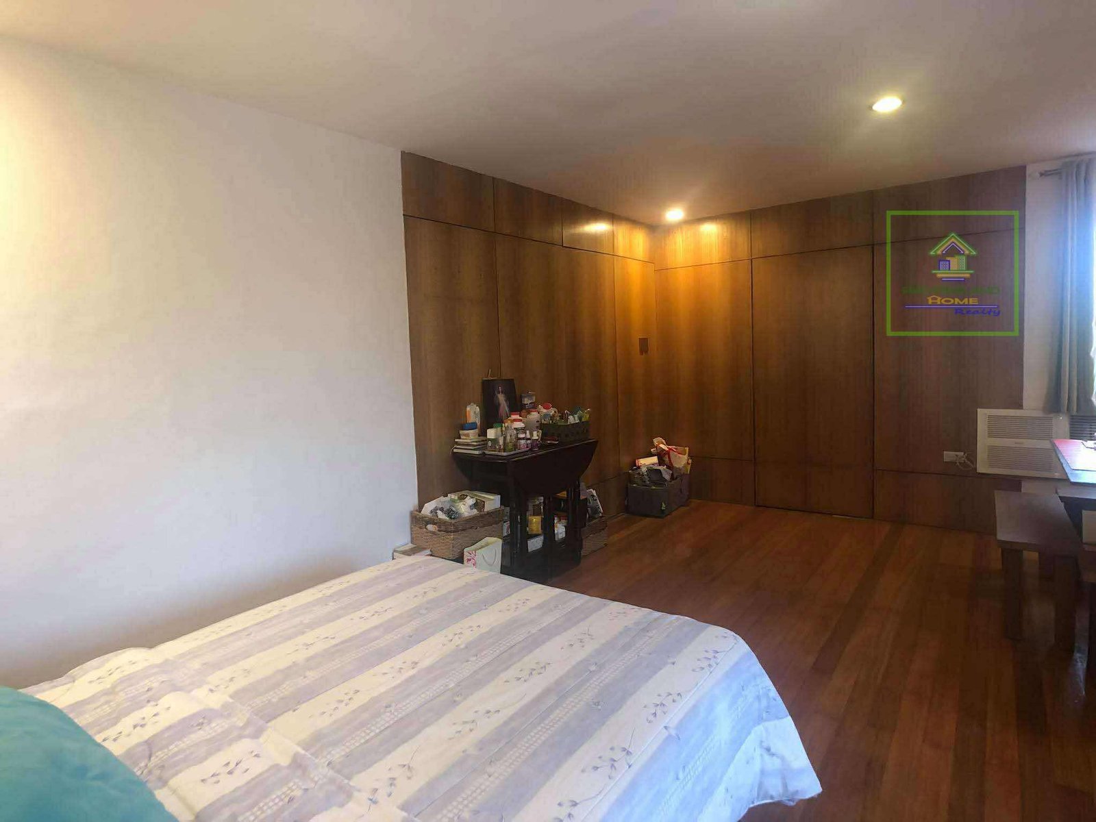 Bedroom with hardwood floors, wooden wall panels, and a bed with striped bedding.