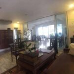 A living room with dark wood furniture, large glass doors, and an outdoor view.