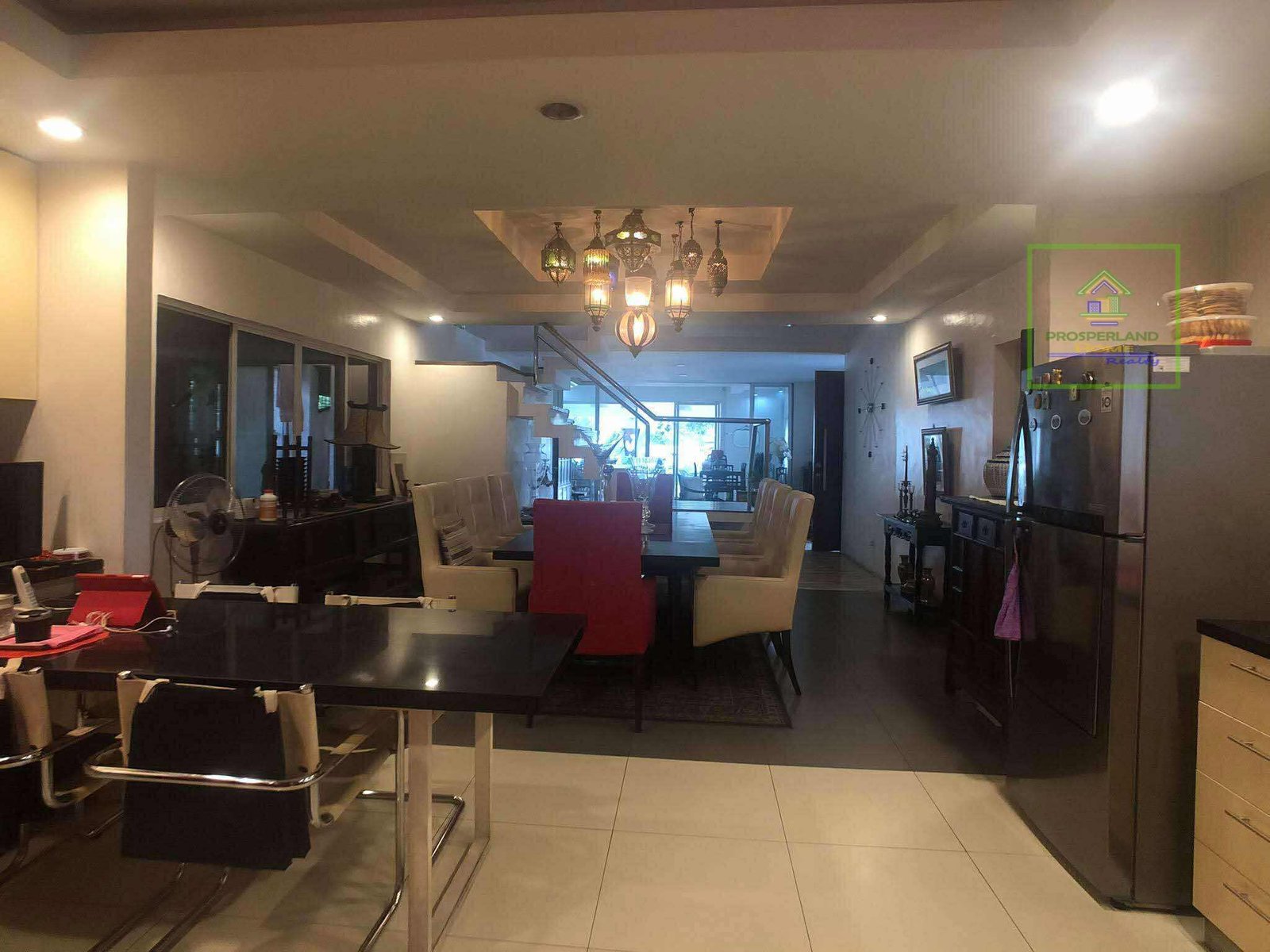 A modern home interior with a dining table, staircase, and chandelier.