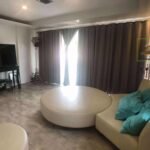 Modern living room featuring a round sofa, TV, and large windows with curtains.