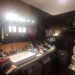 A cluttered bathroom with a large mirror, sink, and toilet.