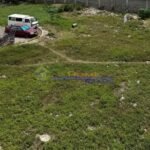 An aerial view of a grassy lot with vehicles parked nearby.