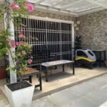 Patio area with seating, a stroller, and a bougainvillea plant in a white pot.