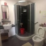 A bathroom interior with a glass shower, sink, and toilet.