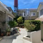 A paved courtyard with potted plants and water tanks on elevated platforms.