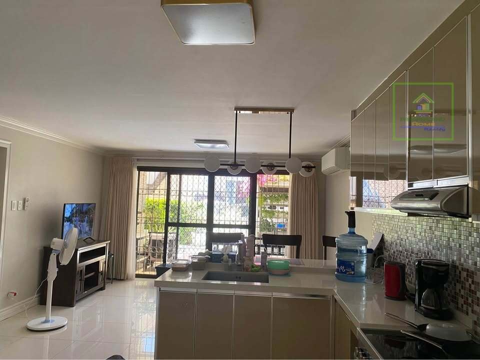 A bright, modern kitchen and living area with tile floors and a sliding glass door to a balcony.