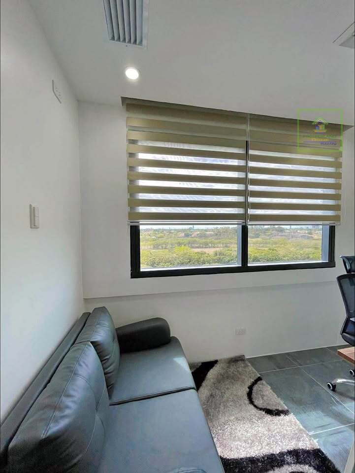 Interior shot of a room with a sofa, rug, and window with blinds.