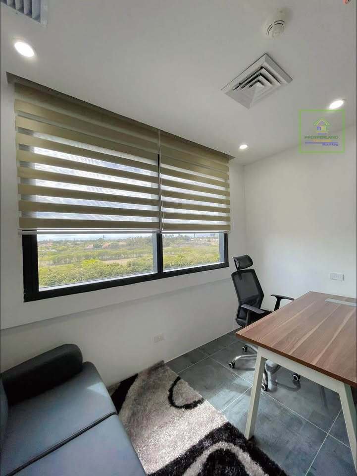 Office space with desk, chair, and sofa near a window with horizontal blinds.