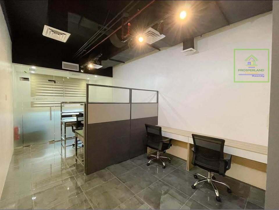 An office space with desks, chairs, dividers, glass-enclosed area, and the Prosperland Realty logo.