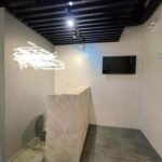 Office reception area with a stone-look desk and a wall-mounted TV.