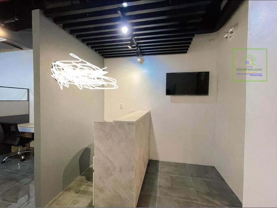 Office reception area with a stone-look desk and a wall-mounted TV.