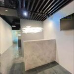 A modern interior with a marble-like countertop, black slat ceiling, and glossy tiled floor.