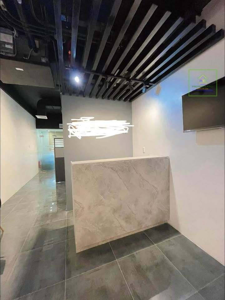 A modern interior with a marble-like countertop, black slat ceiling, and glossy tiled floor.