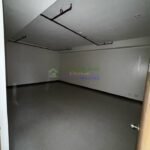 Empty room with gray floors and exposed pipes on the ceiling.