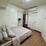 A bedroom with a bed, closet, and wooden floor.