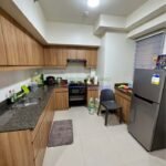 A modern kitchen with wooden cabinets, stainless steel refrigerator, and granite countertops.