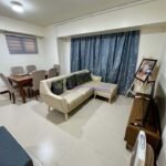 Living room interior with a beige sectional sofa, dining table, TV, and blue curtains.
