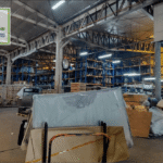Interior of a large warehouse with shelves stacked with windshields and car windows.